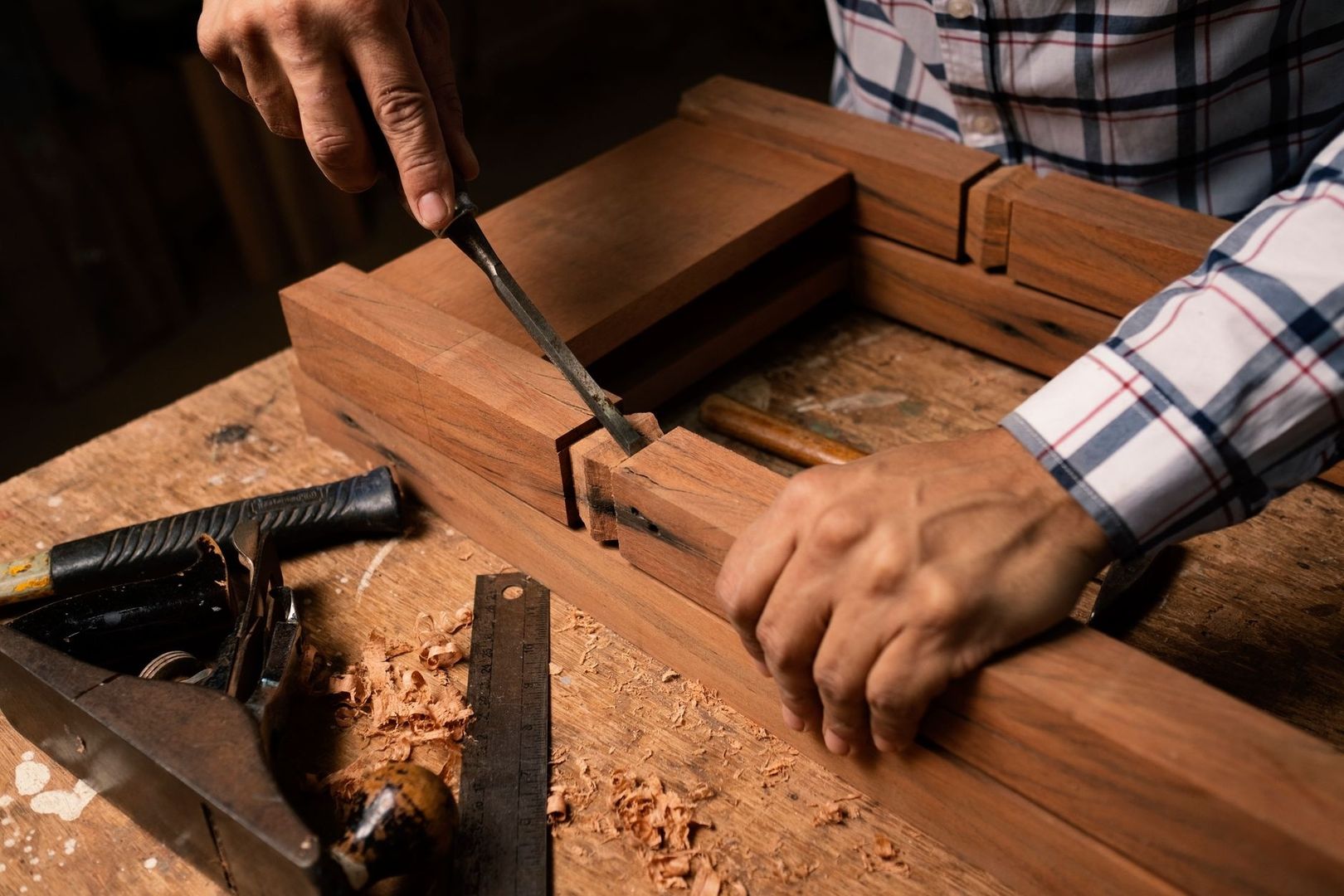 Craftsperson chiseling a wooden mortise joint on a workbench